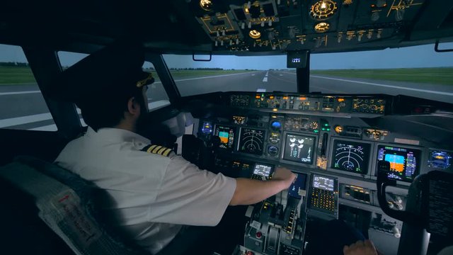 Two pilots are in a cockpit, while a plane goes on a runway. 4K.