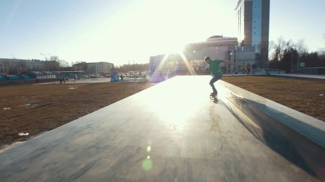 Skateboarder does tricks on the track outdoors in sunset