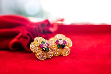 Golden earrings with gem and red gift bag