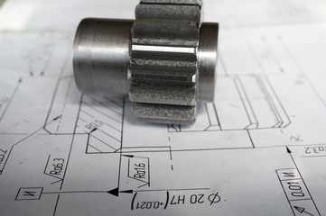A new piece of gear after making the teeth lies on the drawing in the workshop in production
