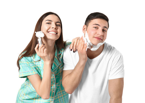 Young woman having fun while her boyfriend shaving on light background