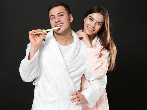 Young man with toothbrush and his girlfriend on dark background
