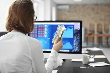 Office employee with money at workplace. Forex concept