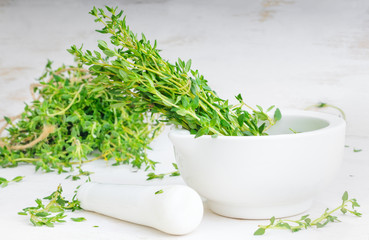 Thyme twigs in the pounder on white wooden table