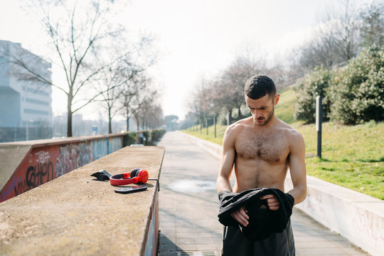 young man outdoor bare chested preparing for training - preparation, body confidence, sport concept