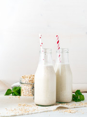 Smoothie with oatmeal, mint for healthy breakfast. Oat milk in glass bottle with tube on white background