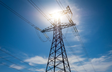 A high voltage power pylons against blue cloudy sky