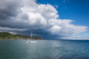 Catamaran by the coastline over dramatic sky