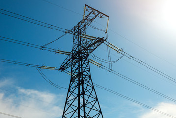 A high voltage power pylons against blue cloudy sky