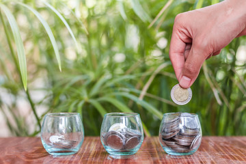 Hand of women putting coin In glass jar , Concept finance business investment