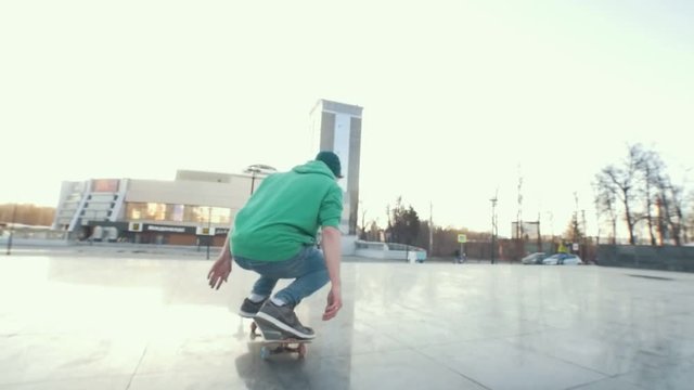 Skateboarder does kickflip on his board in city street at sunset