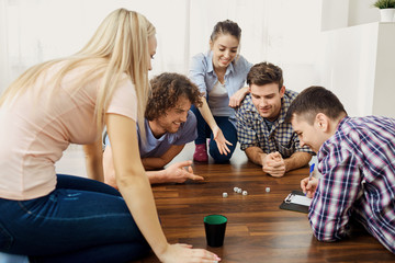 A group of friends play board games on the floor having fun at a party indoors.