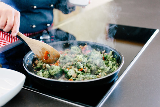 Mid section of chef cooking vegetable dish on induction hob