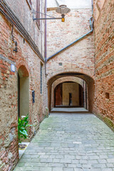 Fototapeta na wymiar Old alley with brick walls and a door entry