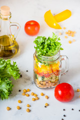 Salad in a jar. Homemade healthy salad from chickpea, tomato, yellow paprika, cucumber and green lettuce