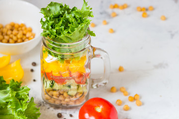 Salad in a jar. Homemade healthy salad from chickpea, tomato, yellow paprika, cucumber and green lettuce