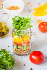 Salad in a jar. Homemade healthy salad from chickpea, tomato, yellow paprika, cucumber and green lettuce