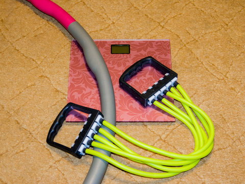 A set of items for sports at home. Rubber expander and a Hoop. Scales are floor.