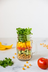 Salad in a jar. Homemade healthy salad from chickpea, tomato, yellow paprika, cucumber and green lettuce