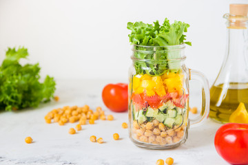 Salad in a jar. Homemade healthy salad from chickpea, tomato, yellow paprika, cucumber and green lettuce