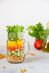 Salad in a jar. Homemade healthy salad from chickpea, tomato, yellow paprika, cucumber and green lettuce