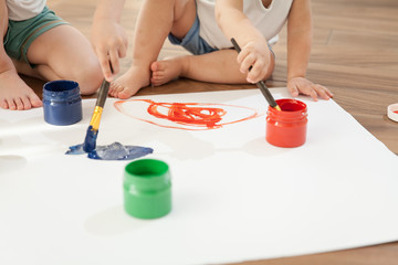 Fototapeta na wymiar Children draw bright colors on paper, sitting on the floor