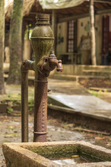 Old colonial water pump in mexican town. Although its parts are still standing, it is now rusty and out of order. Quiet spring showers make it wet and even more beautiful