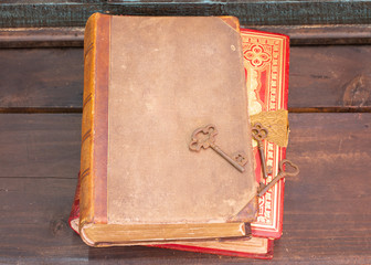 Two antique books on a wooden shelf with some old skeleton keys 