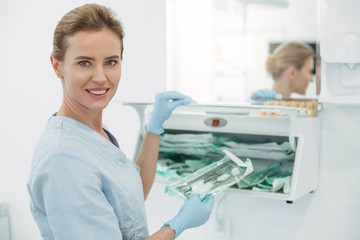 Fototapeta premium In high spirits. Inspired professional dentist smiling and holding some instruments