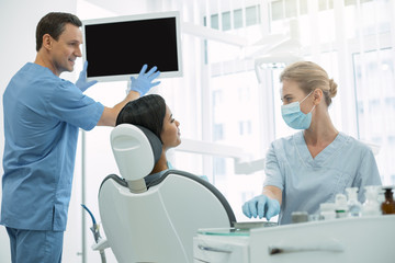 Do not worry. Charming blond dentist wearing a uniform and looking at her patient