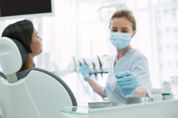 My instruments. Determined skilled dentist wearing a uniform and taking her instrument