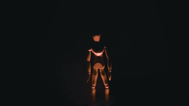 wooden man on black background with backlight from below