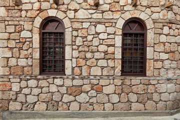 Fototapeta na wymiar Two windows on old stone wall