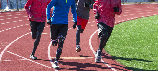 Four boys running on a track in winter