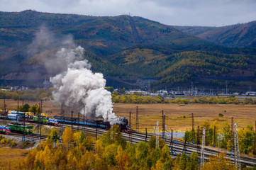 Old steam locomotive in the Circum-Baikal Railway with smoke in autumn