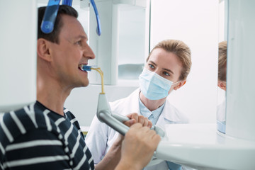 Taking care. Determined dark-haired man opening his mouth and having a dental device in it