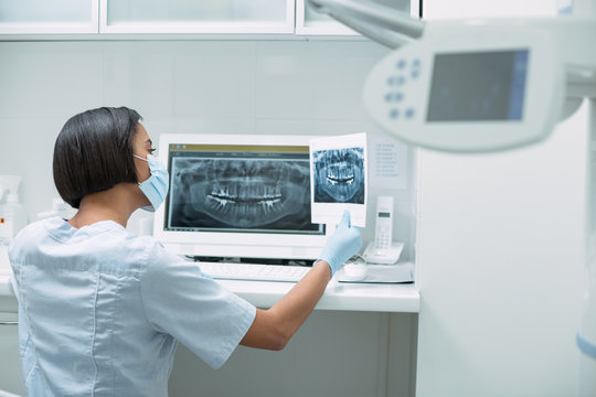 My modern device. Professional dark-haired dentist holding an image and working on her advanced device