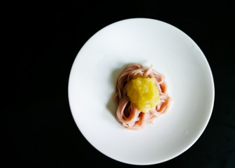 Baby pasta served with fruits and vegetables puree on a white plate.
