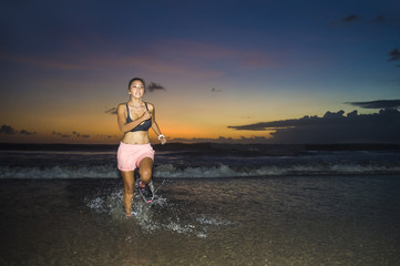 Fototapeta na wymiar young Asian sport runner woman in running workout training at sunset beach with orange sunlight evening sky in healthy lifestyle and wellness activity