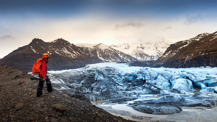 professional photographer with camera and tripod in winter. professional photographer looking to glacier in Iceland.