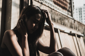 Outdoors portrait of beautiful young sad teen girl sitting on stairs with little sunshine in the evening. Lonely young women sitting and worrying about life.  Stressed women. Life issue and problem.