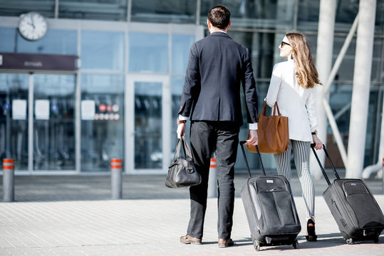 Business couple walking together to the airport entrance carrying suitcases and bags