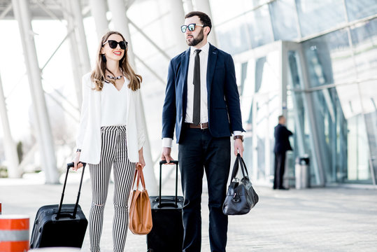 Business Couple Walking With Luggage Near The Airport During The Business Trip