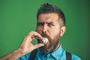 Bearded man chewing lightbulb when inspiring creativity. Light bulb for global power&energy concept. Male with lightbulb in mouth. Business man with light bulb idea. Caucasian man with bulb in mouth.