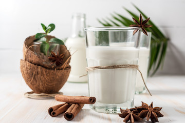 Shell of coconut and coconut milk in glass with cinnamon on wooden table.