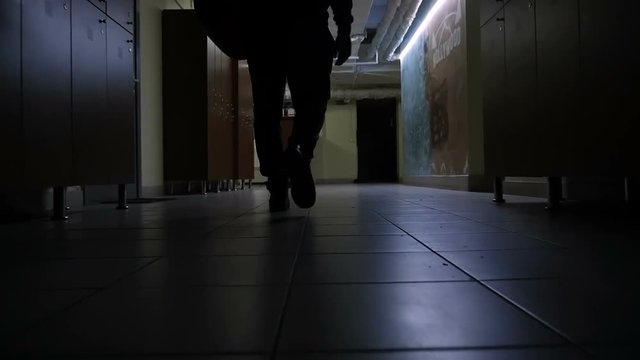 Slow motion mideo of man going to gym in the dark corridor