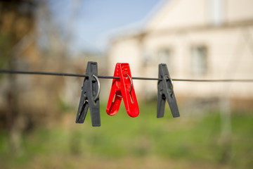 Fototapeta na wymiar Three clothespins on the clothesline near the house. Wash. Red and black color.