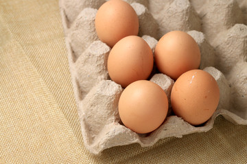 Fresh chicken eggs In the thirty box paper and have empty space for egg on cream fabric background.