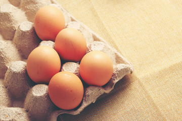 Fresh chicken eggs In the thirty box paper and have empty space for egg on cream fabric background.