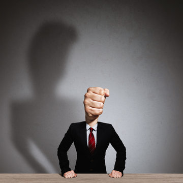 The man in a suit with a head in the form of a fist. Metaphor of an angry boss.